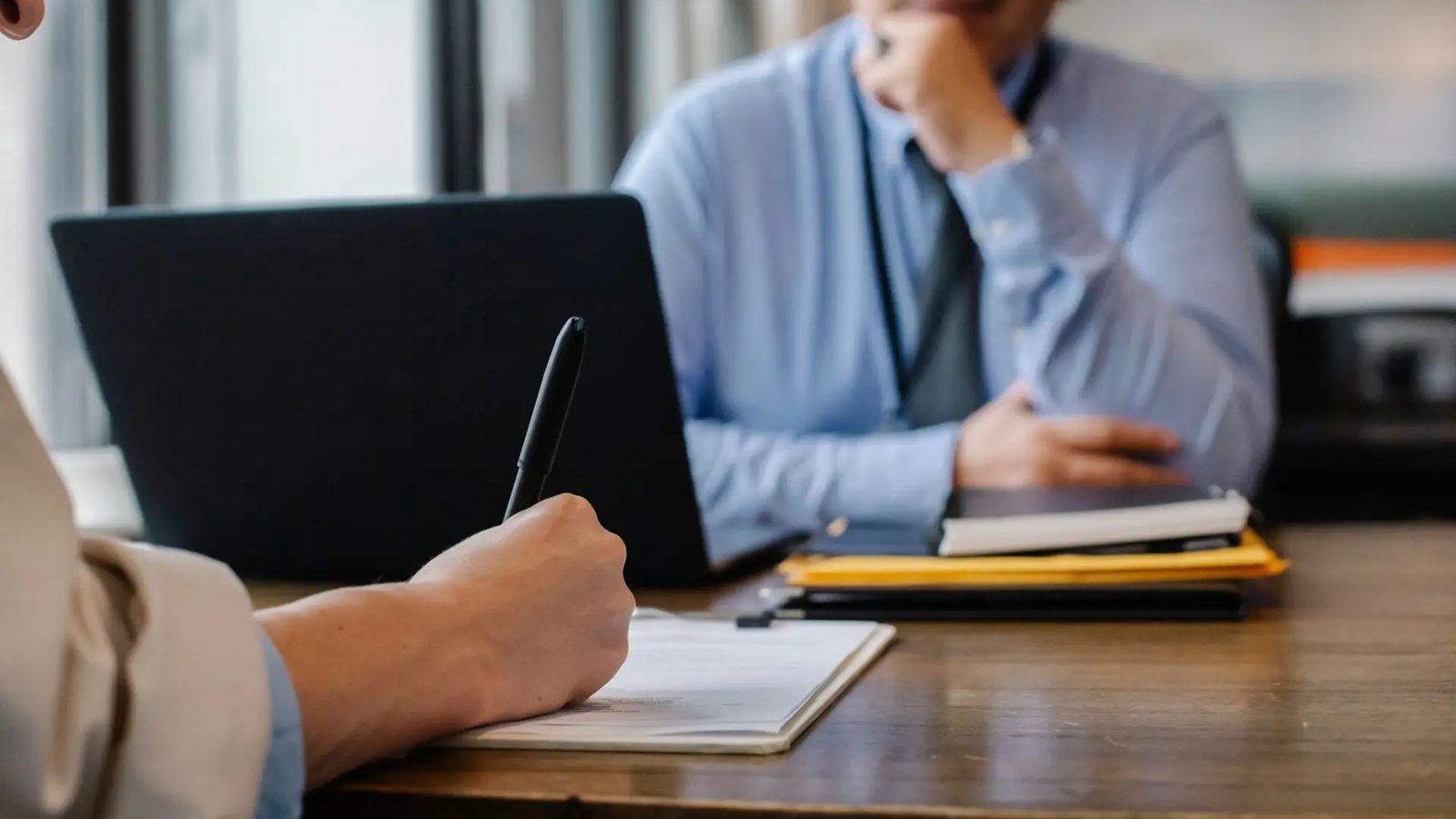 Gestor fazendo anotações durante conversa de avaliação
